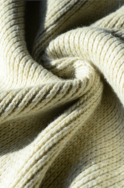 Stoffentextuur van een zachte gele gebreide sweater. Macro afbeelding van de structuur van de bindingen in garens