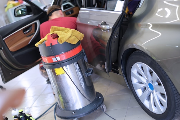 Stofzuiger staande in de buurt van auto wasmachine man close-up