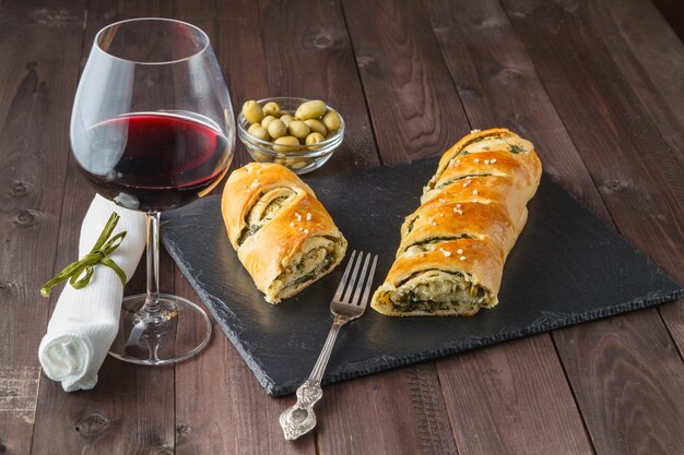 Stokbrood met olijven en glas rode wijn op tafel