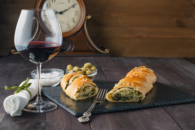 Stokbrood met olijven en glas rode wijn op tafel