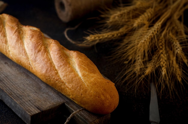 Stokbrood van tarwebloem op oude houten plank met aartjes