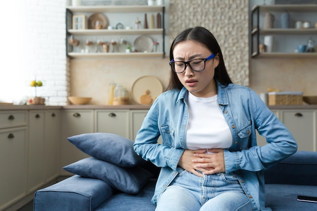 Stomach disorder a young beautiful asian woman holds her stomach with her hands feels severe pain