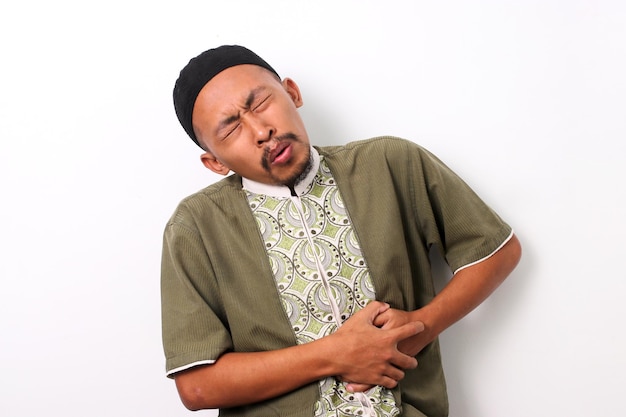Боль в животе во время Рамадана Индонезийский мужчина в исламской одежде
