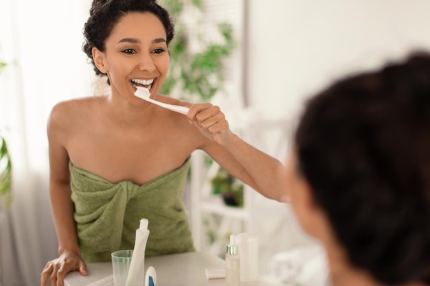 Stomatologie tandhygiëne concept mooie jonge dame in handdoek tandenpoetsen met tandenborstel in de buurt