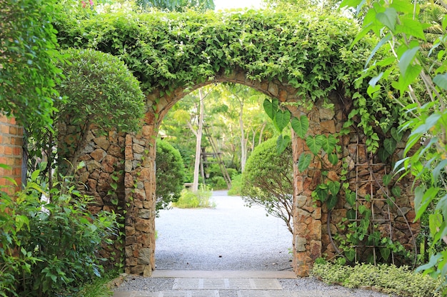 Stone arch entrance gate covered with ivy. Archway to the park.