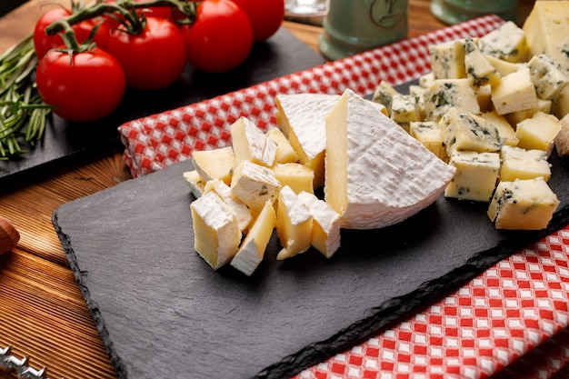 Stone board with cut cheese on wooden table close up