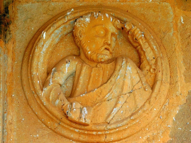 A stone carving of a man with a beard and a hat on it.