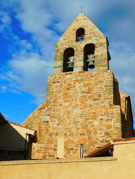 A stone church with bells on the top of it