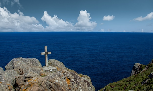 Foto croce di pietra sulla sommità di una collina di fronte al mare in galizia, spagna