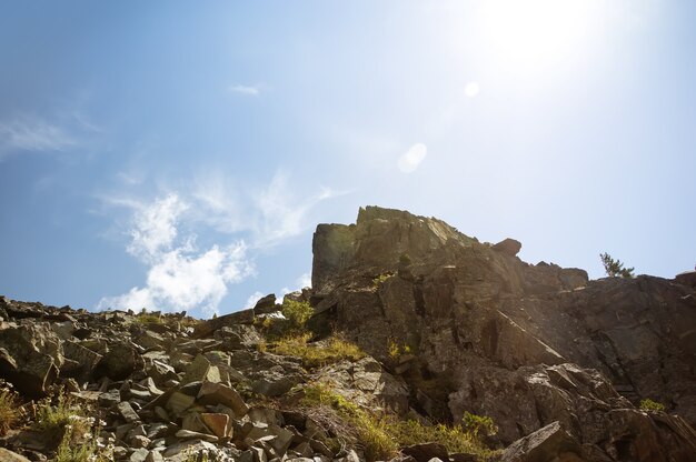 Stone deposits on the top of a high mountain on the background of blue sky with a bright sun in a summer day