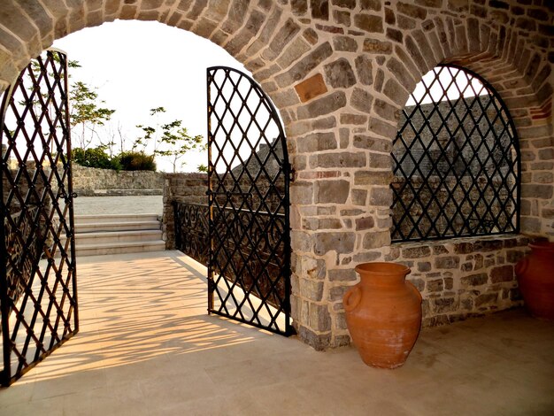 Stone entrance arch and windows with metal bars and gates Red ceramic jug