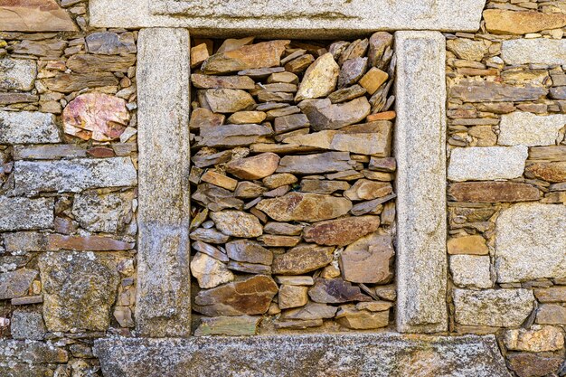 Stone house with window boarded up with old stones.