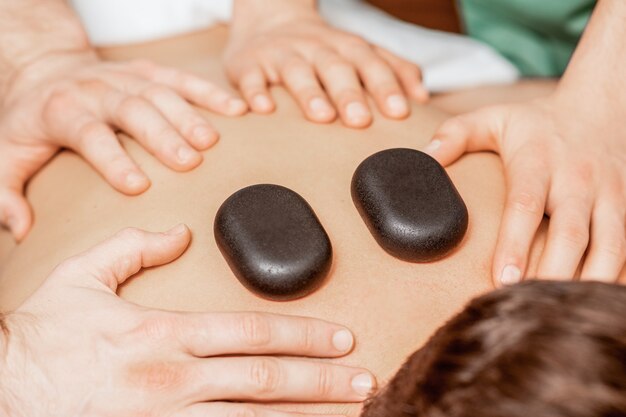 Stone massage on back of man.