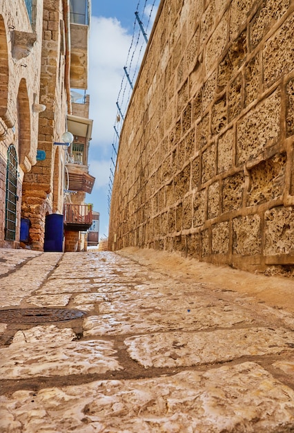 Stone narrow streets of the Old City of Jaffa against blue sky with clouds