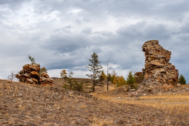 Stone outcrops in the steppe. A gloomy sky with clouds is visible. Horizontal.