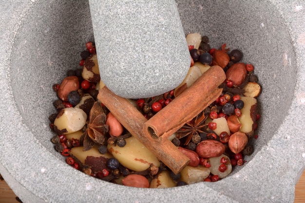 Stone pestle grinding anise nuts pepper and cloves on wood