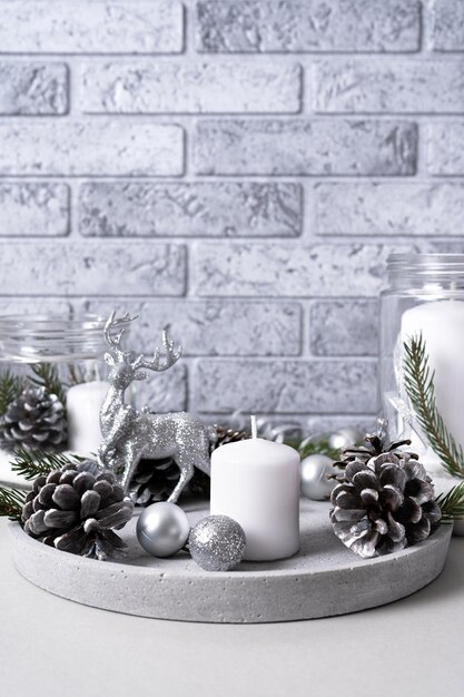 Stone plate with candles fir branches and pine cones with silver Christmas decorations