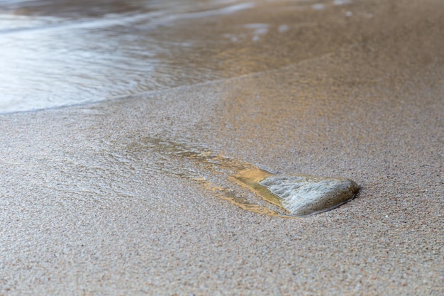 Stone on the seashore with water slipping around it