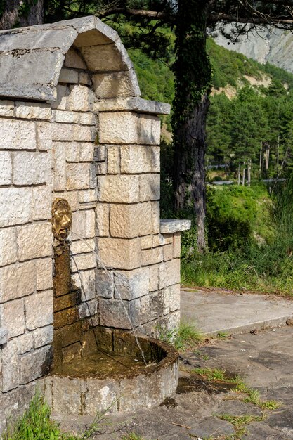 Крупный план каменного источника с холодной чистой водой в горах в солнечный летний день, регион Цумерка, Греция, горы Пиндос