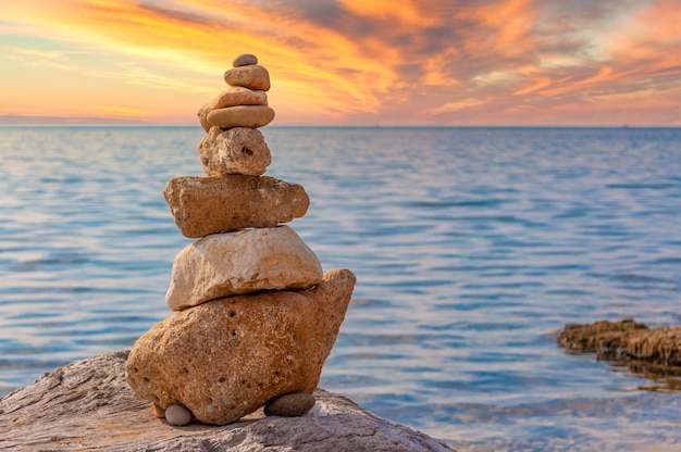 Stone stacking on the coast at sunset with dramatic sky