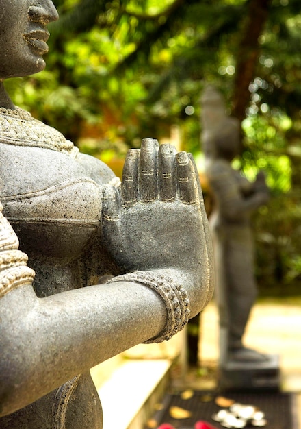 Foto statua in pietra di una donna indiana che tiene le mani insieme in namaste india