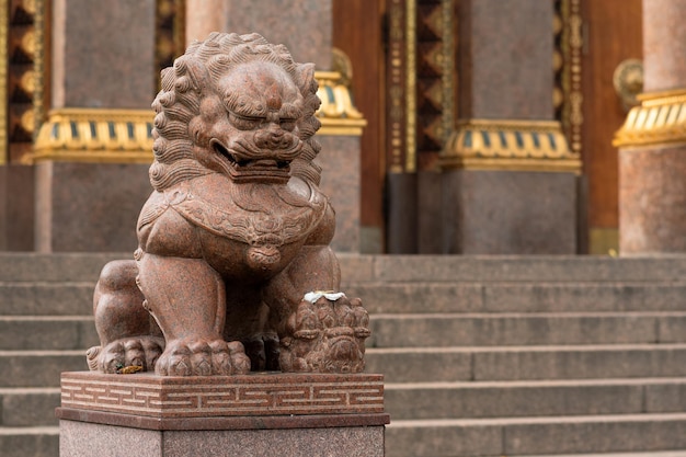 Photo stone statue of a lion at the entrance to the buddhist datsan gunzechoinei