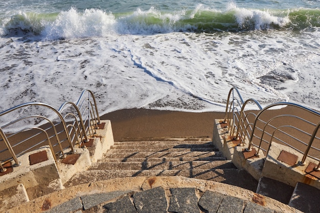 Stone steps descending on a sandy beach with a promenade