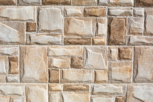 Stone tiles made of rectangular fragments of beige and sand color. Background, texture.