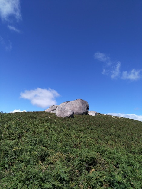 Stone wall on field against blue sky