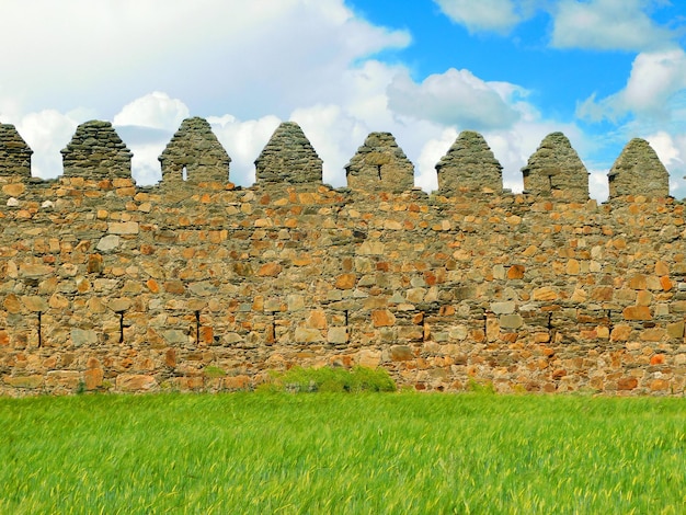 A stone wall in a field with a blue sky behind it