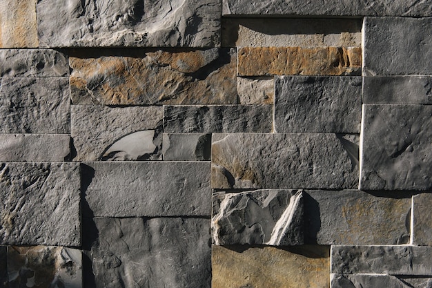 Stone wall in sunlight sharp shadows emphasize the textere different size cut out gray marble wall