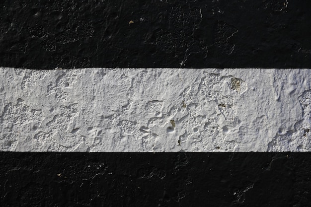 Каменная стена с черной краской с серебряной полосой посередине. Фото высокого качества