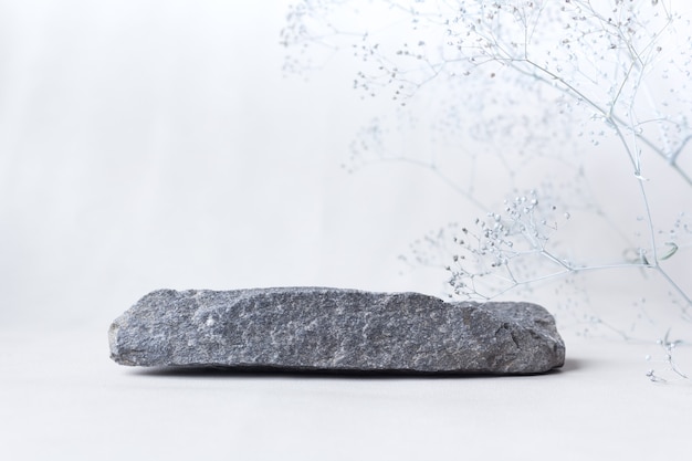 Photo stone with flowers on a light background. catwalk for the presentation of products and cosmetics.