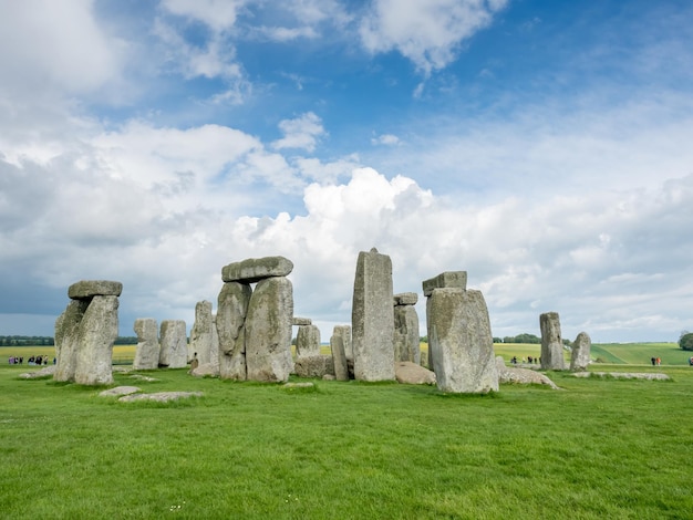 Stonehenge with unrecognized tourist near Salisbury England under cloudy sky