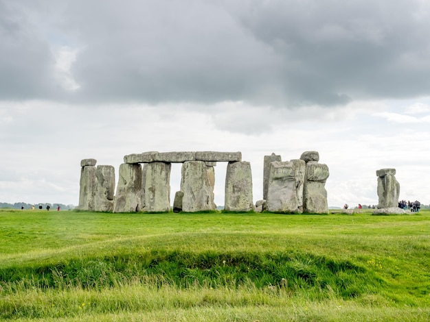 Stonehenge with unrecognized tourist near Salisbury England under cloudy sky