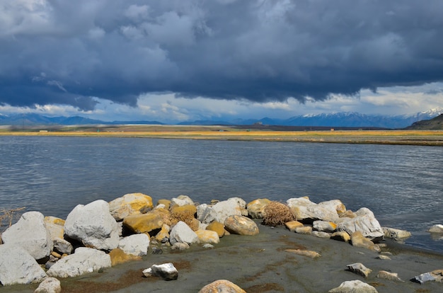 Stones covered with salt against the background of a salt lake and rain clouds. Great Salt Lake in Utah, USA