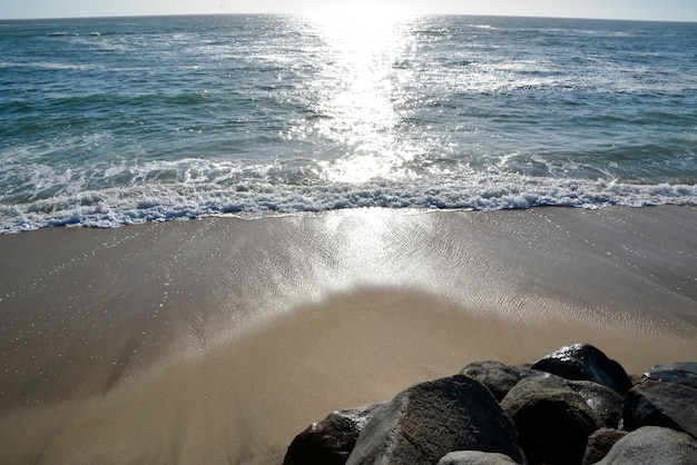 Stones lie on the sandy sea beach Foamy waves roll in