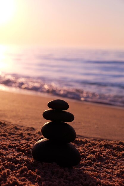 Foto piramide di pietre sulla spiaggia al tramonto