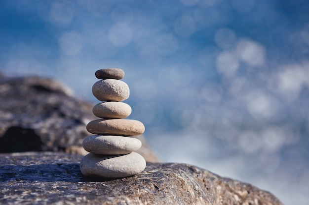 Stones pyramid on pebble beach stability zen harmony balance concept With blur sea background on a sunny day