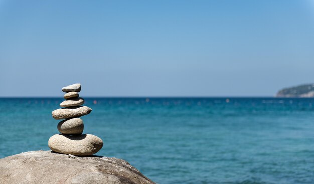 Stones pyramid on pebble beach symbolizing stability, zen, harmony, balance. 