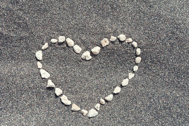 Stones in the shape of heart on the black sand.