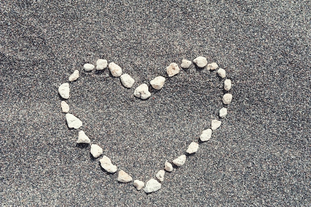 Pietre a forma di cuore sulla sabbia nera.