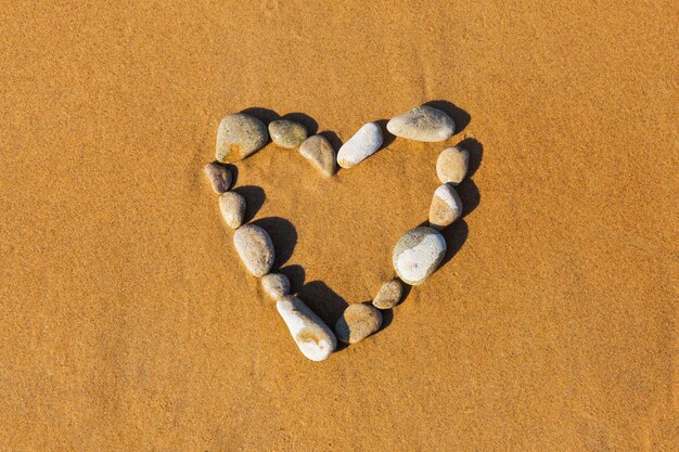 Stones in the shape of heart on yellow wet sand