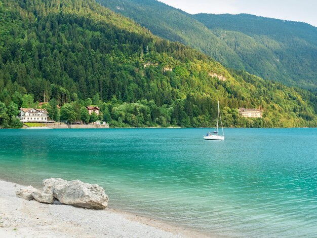 Photo stones on shore of blue green water of mountain lake molveno at foot of the brenta dolomites italy