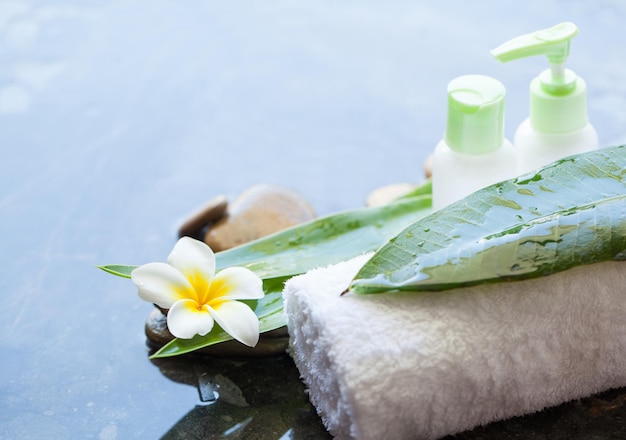 Stones towel bottles leaves for massage treatment on dark background with copy space