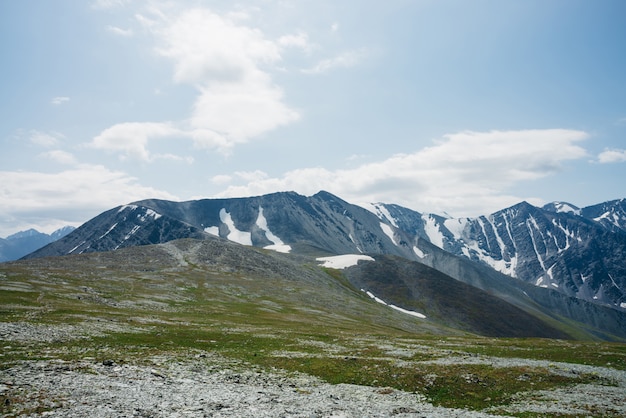 Stony meadow with green grass and big mountain ridges