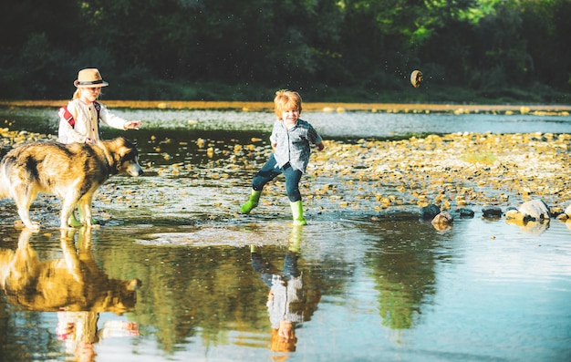 石の川川の子供たちで遊んでいる小さな男の子と女の子が石を投げる子供たちがmouで水で遊ぶ