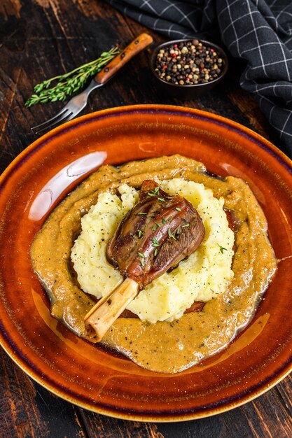 Stoofpotje Lamsschenkel met aardappelpuree op een bord. Zwarte achtergrond. Bovenaanzicht.