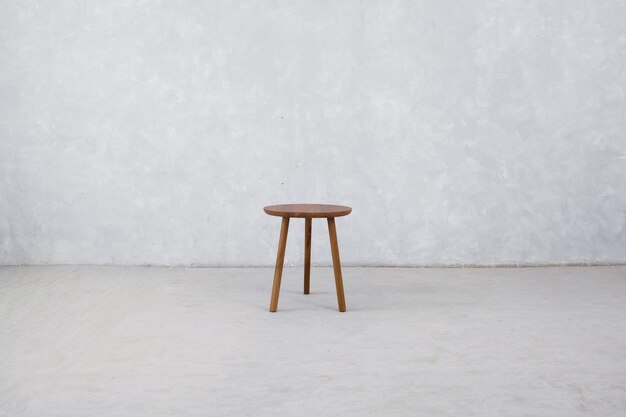 A stool in a white room with a white wall behind it.