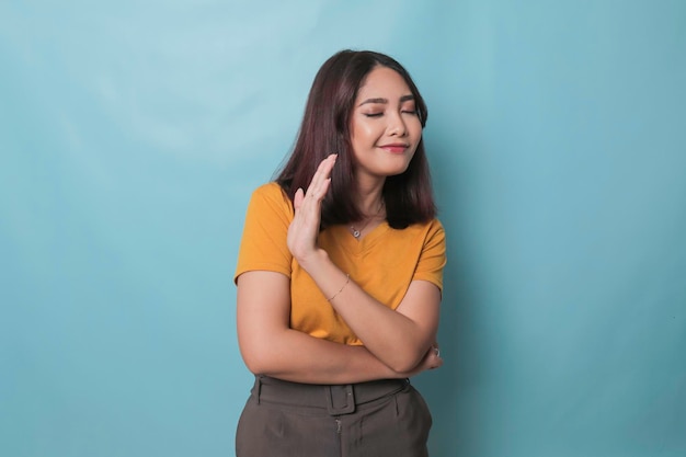 Stop Concerned Asian woman showing refusal sign saying no raise awareness standing over blue background